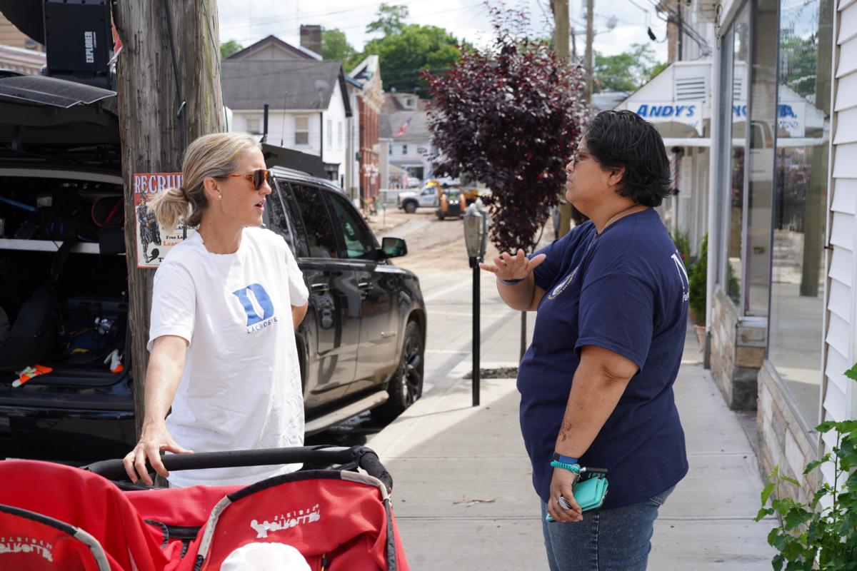 DeeDee Moreno informed a resident about available aid to people impacted by the historic flood on Main Street in Highland Falls, N.Y., on July 10, 2023. (Cara Ding/The Epoch Times)