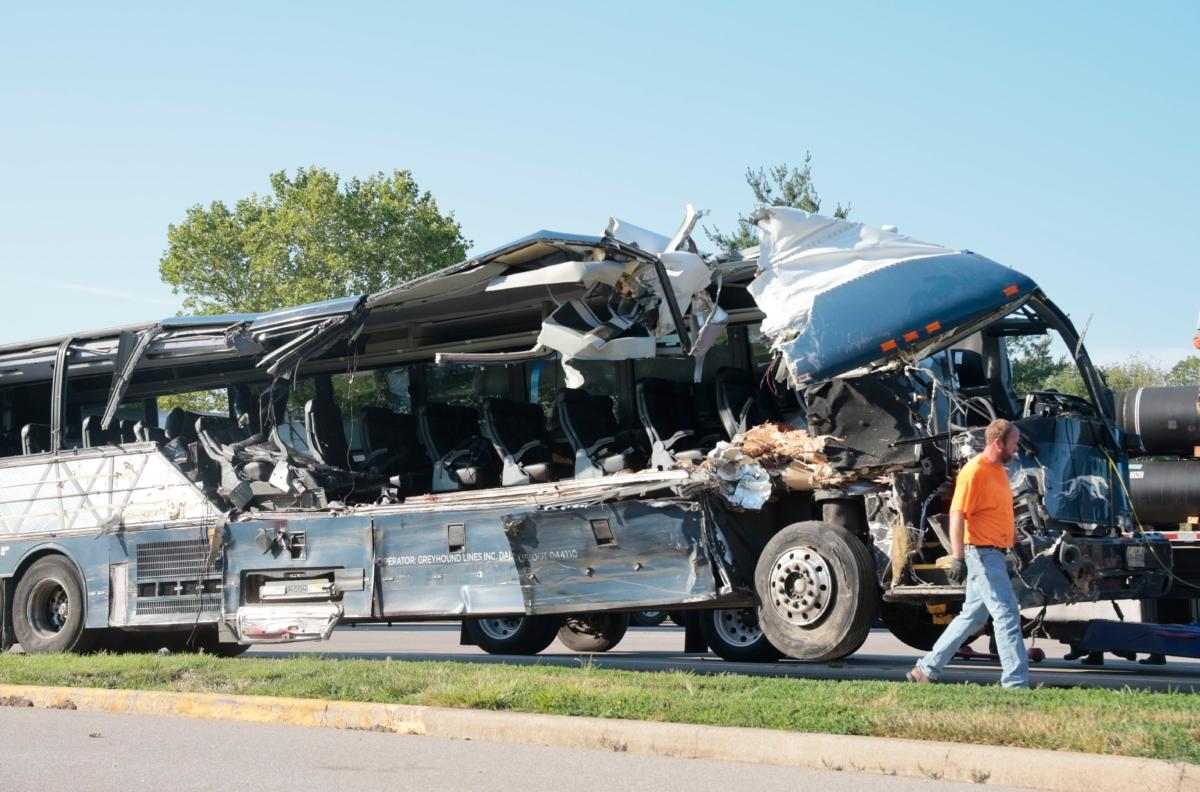 A worker helps clear the wreckage of a Greyhound bus that collided with tractor-trailers on the exit ramp to a rest area on westbound Interstate 70 in Highland, Ill., on July 12, 2023. (Christian Gooden/St. Louis Post-Dispatch via AP)