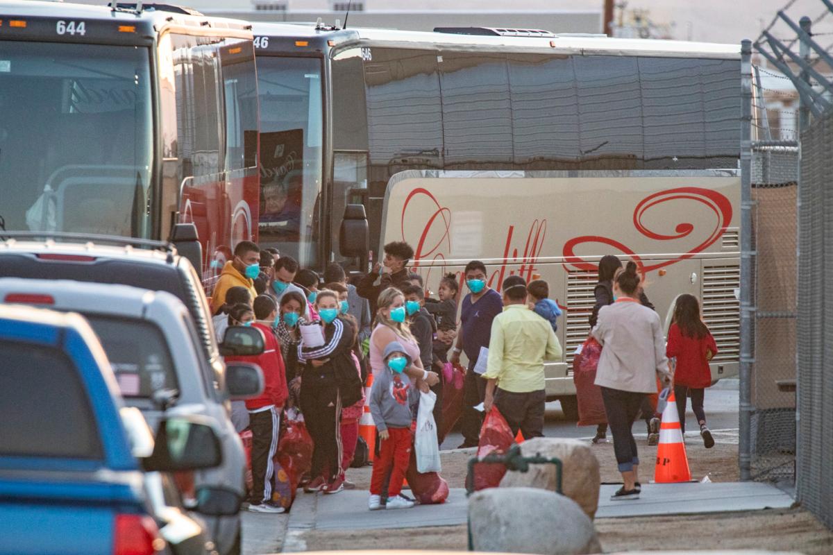 Illegal immigrants are moved onto charter buses and transfered to a migrant shelter after being caught by border patrol agents in Indio, Calif., on Oct. 18, 2021. (John Fredricks/The Epoch Times)