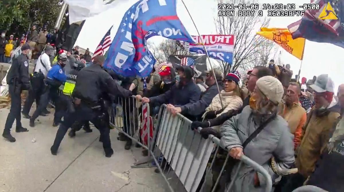 Capitol Police Officer Brian Sicknick (blue jacket, left) and other officers pull back against rioters trying to topple police barriers on the Capitol's west plaza on Jan. 6, 2021. (Metropolitan Police Department/Screenshot via The Epoch Times)