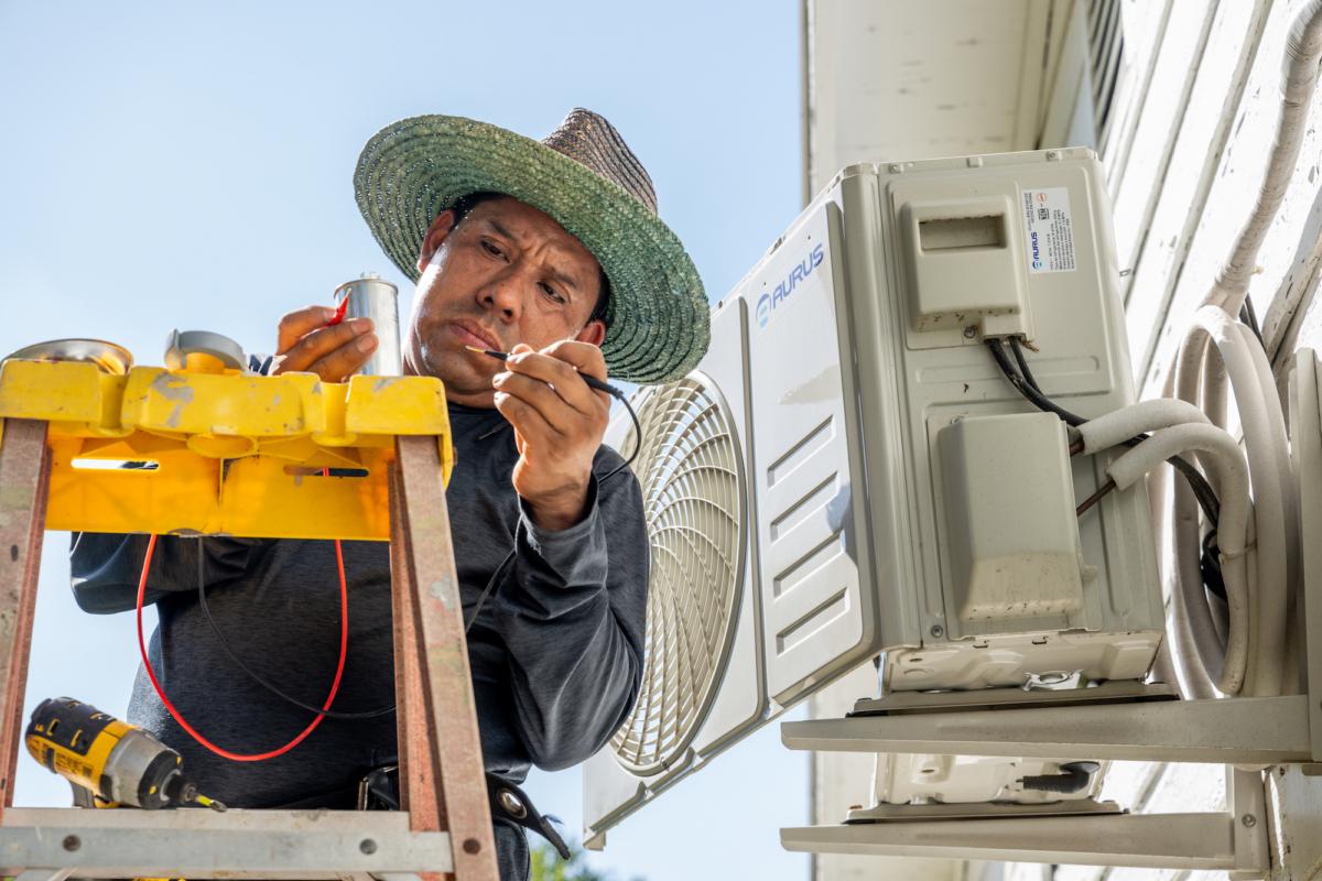 A technician repairs an air conditioning unit in Austin, Texas, on July 10, 2023. (Brandon Bell/Getty Images)