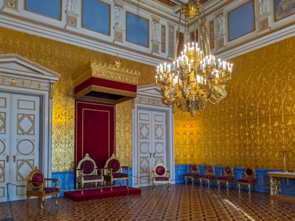 The king’s waiting room, in an eclectic mix of styles, serves as the royal audience chamber. The furniture is decorated with red damask, and a Baroque chandelier hangs from the ceiling. The rest of the room features the Neoclassical style with symmetric doors, the wall borders, and blue and gold wall paneling. (Andrus Ciprian/Shutterstock)