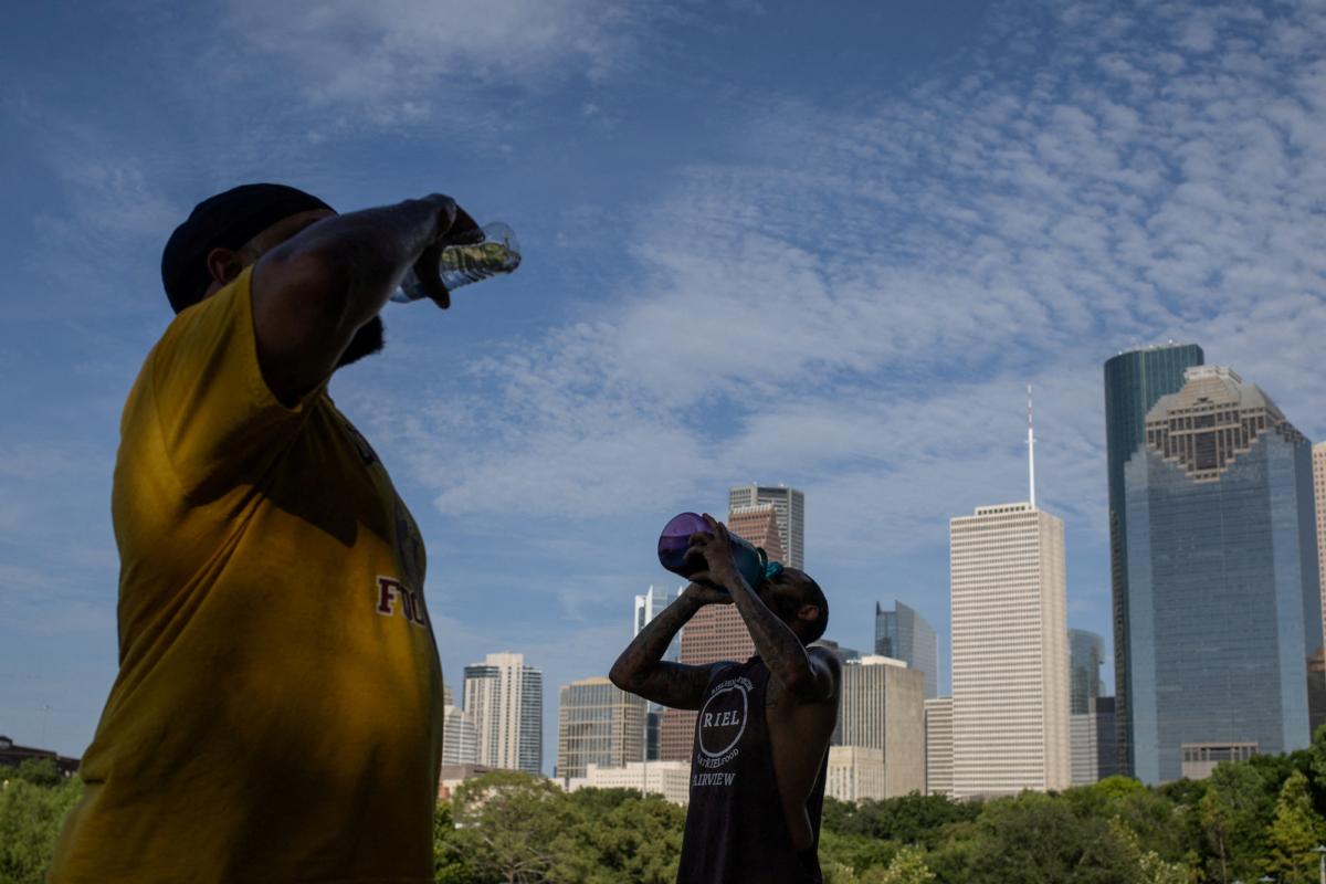 Val Martin and Ashford Joseph rehydrate after climbing stairs in Eleanor Tinsley Park as temperatures hit 100 degrees Fahrenheit in Houston, Texas, on July 12, 2023. (Adrees Latif/Reuters)