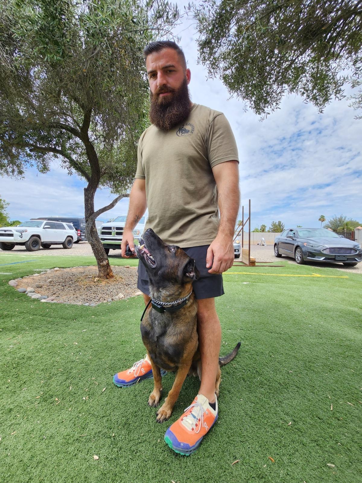 Chris Kamma of K9 Defense in Scottsdale, Ariz., instructs protection dog "Ditto" to stay by his feet on July 11, 2023. (Allan Stein/The Epoch Times)