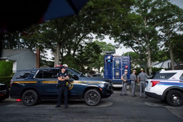 Police officers stand guard near the house where a suspect has been taken into custody on New York's Long Island in connection with a long-unsolved string of killings, known as the Gilgo Beach murders, in Massapequa Park, N.Y., on July 14, 2023, (Eduardo Munoz Alvarez/AP)
