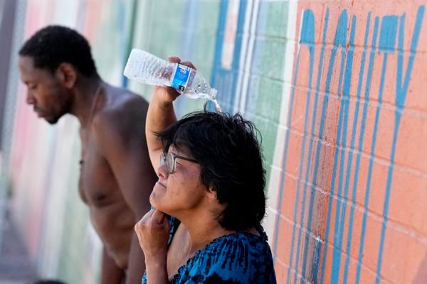 People, who are homeless, try to cool down with chilled water outside the Justa Center, a day center for homeless people 55 years and older in downtown Phoenix, on July 14, 2023. (Matt York/AP Photo)