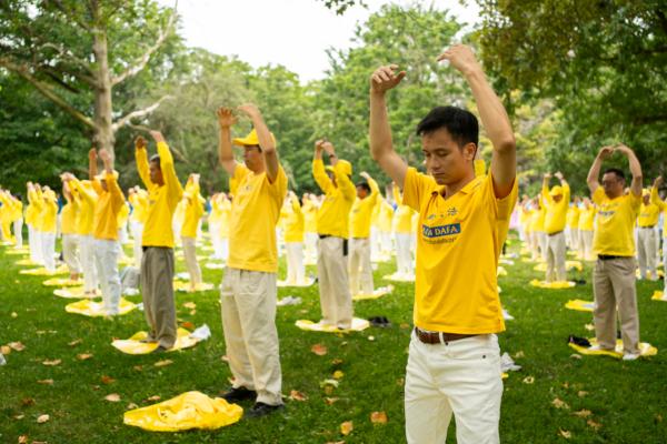 Falun Gong adherents perform the practice's meditative exercises at Queen's Park in Toronto on July 15, 2023.  (Evan Ning/The Epoch Times)