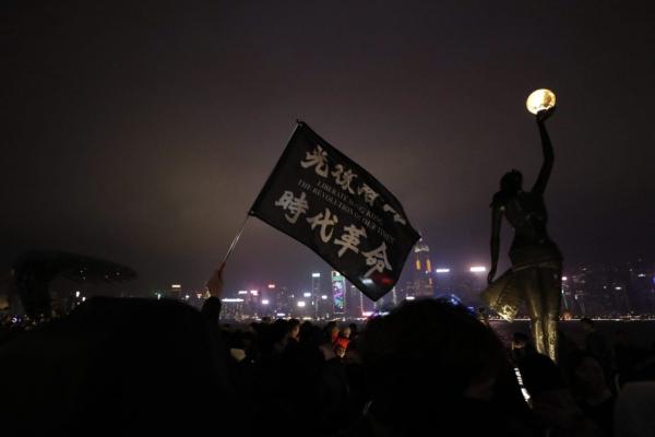 A protester holds a flag reading "Liberate Hong Kong, the Revolution of Our Times" during a demonstration in Hong Kong, Dec. 31, 2019. (The Canadian Press/AP-Lee Jin-man)