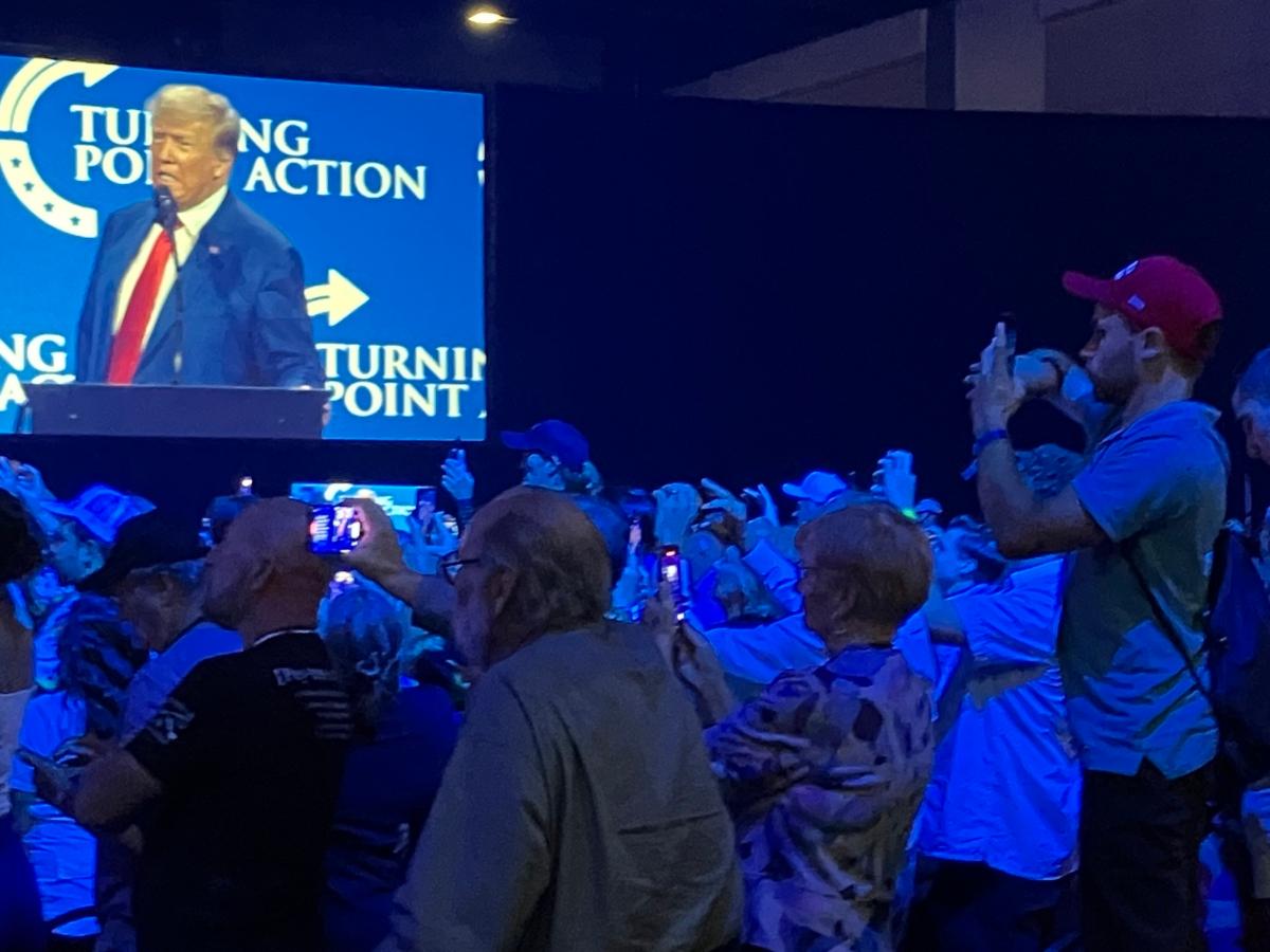 Audience members stand on chairs to photograph former President Donald Trump at a speech for the Turning Point Action Conference at the Palm Beach County Convention Center on July 15, 2023. (Janice Hisle/The Epoch Times)