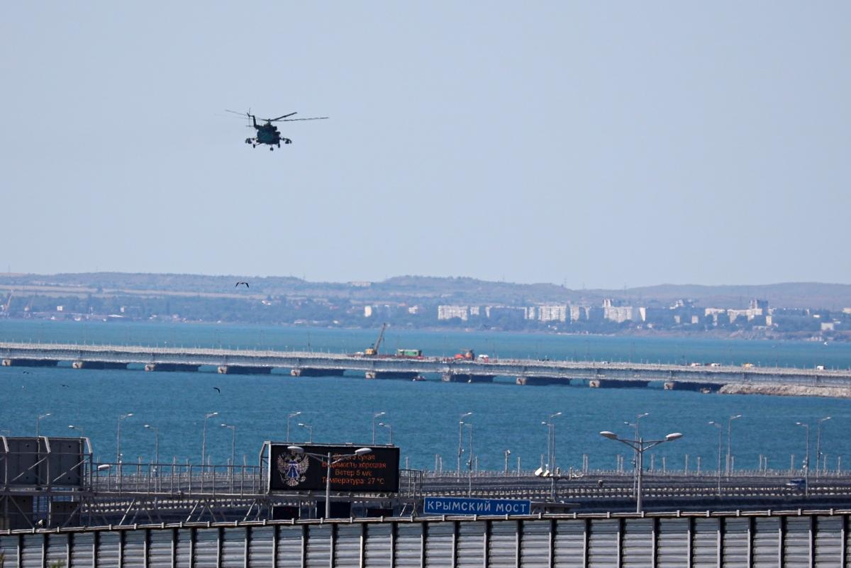 A Russian military helicopter flies over damaged parts of an automobile link of the bridge connecting the Russian mainland and the Crimean peninsula over the Kerch Strait, on July 17, 2023. (AP Photo)