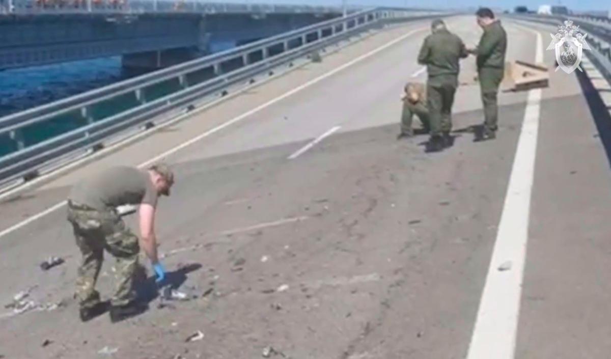 Investigators work at an automobile link of the Crimean Bridge connecting Russian mainland and Crimean peninsula over the Kerch Strait not far from Kerch, Crimea, in a handout photo taken from video released on July 17, 2023. (Investigative Committee of Russia via AP)