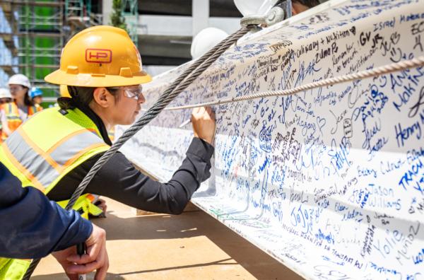 Workers sign an iron beam soon to be inserted into a building frame as construction crew work on a new medial facility at the University of California–Irvine in Irvine, Calif., on July 13, 2023. (John Fredricks/The Epoch Times)