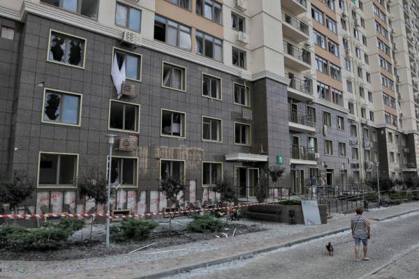 A local resident walks with a dog next to a building damaged during Russian missile and drone strikes near Odesa, Ukraine, on July 19, 2023. (Stringer/Reuters)