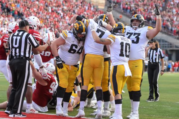 Quarterback Spencer Petras #7 of the Iowa Hawkeyes and offensive lineman Cody Ince #73 and wide receiver Arland Bruce IV #10 and offensive lineman Kyler Schott #64 celebrate scoring the winning touchdown against the Nebraska Cornhuskers in the second half at Memorial Stadium in Lincoln, Nebraska, on Nov. 26, 2021. (Steven Branscombe/Getty Images)