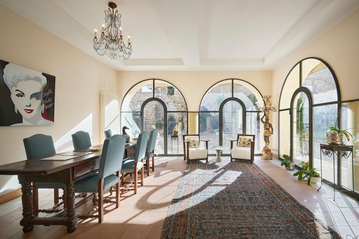 The formal dining room features tile flooring, a soaring ceiling, and floor-to-ceiling glass walls looking out over the property’s inner courtyard. (Courtesy of Concierge Auctions, Toptenrealstatedeals.com)