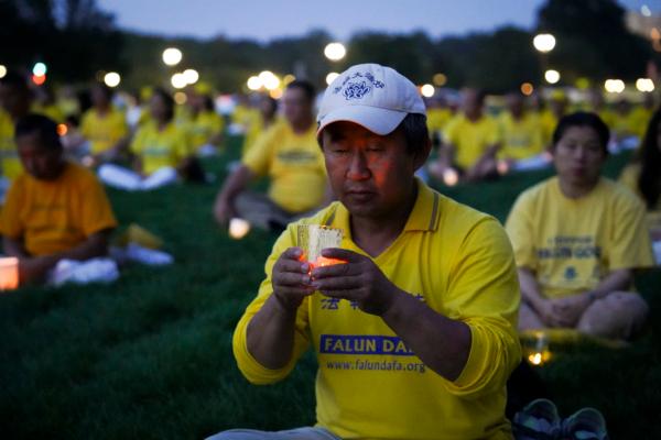 Liang Guiyu, a Falun Gong adherent from Flushing, New York, holds a candle during a candlelight vigil in memory of Falun Gong practitioners who passed away due to the Chinese Communist Party’s persecution, at the National Mall in Washington on July 20, 2023. (Madalina Vasiliu/The Epoch Times)