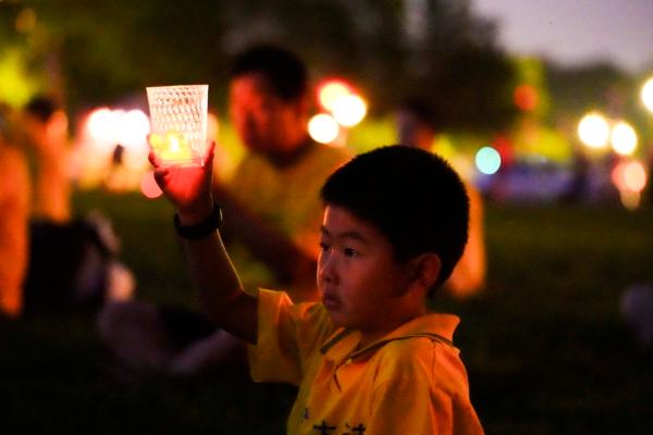 Falun Gong adherents hold candles during a candlelight vigil in memory of Falun Gong practitioners who passed away due to the Chinese Communist Party’s 24 years of persecution, at the National Mall in Washington on July 20, 2023. (Madalina Vasiliu/The Epoch Times)