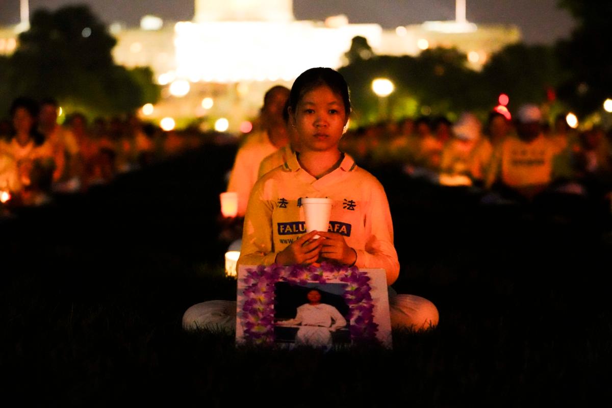 Falun Gong adherents hold candles during a candlelight vigil in memory of Falun Gong practitioners who passed away due to the Chinese Communist Party’s 24 years of persecution, at the National Mall in Washington on July 20, 2023. (Madalina Vasiliu/The Epoch Times)