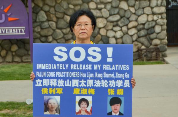 Kang Shuzhi holding a banner calling for the rescue of her relatives arrested by police in China at a candlelight vigil in front of the Chinese Consulate in Los Angeles on July 18, 2023. (Alex Lee/The Epoch Times)