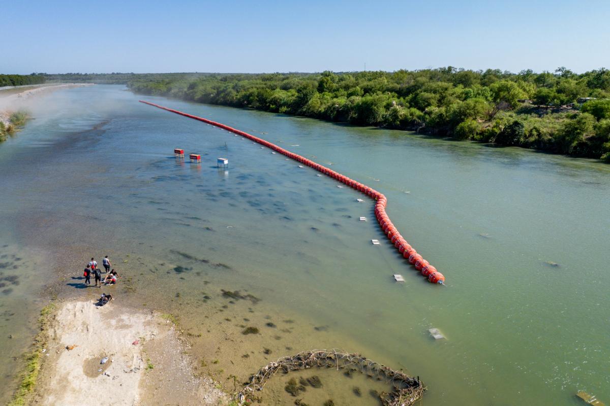 People rest on an island while attempting to cross the Rio Grande river into the United States, in Eagle Pass, Texas, on July 18, 2023. (Brandon Bell/Getty Images)