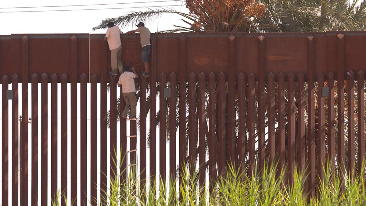 Illegal immigrants use a rope ladder to climb over the wall separating the United States from Mexico in El Centro, Calif., on Oct. 6, 2022. (Allison Dinner/AFP via Getty Images)