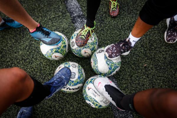 Female players pose for a picture with their feet on balls during a training session led by women's football coach Dilma Mendes, 59, at the Arena 2 de Julho Football School located in the city of Camacari, Bahia state, Brazil, on July 5, 2023. (Rafael Martins/AFP)