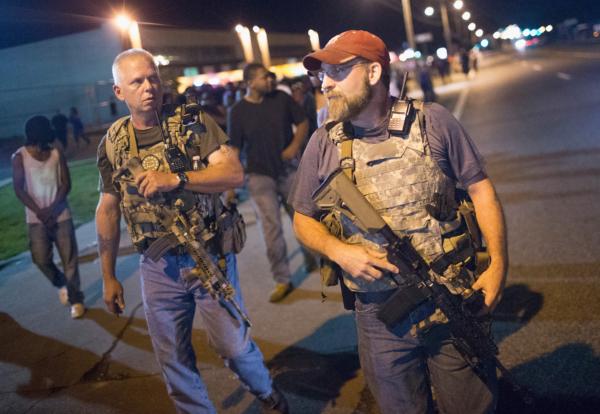 Oath Keepers, carrying rifles, walk along West Florrisant Street as demonstrators, marking the first anniversary of the shooting of Michael Brown, protest on Aug. 10, 2015 in Ferguson, Missouri. Brown was shot and killed by a Ferguson police officer on August 9, 2014. His death sparked months of sometimes violent protests in Ferguson. (Scott Olson/Getty Images)