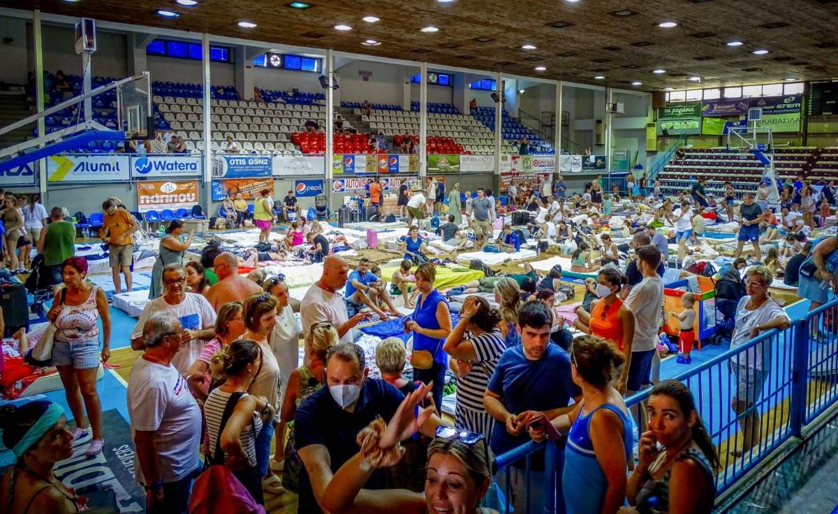 Evacuees sit inside a stadium following their evacuation during a forest fire on the island of Rhodes, Greece, on July 23, 2023. (Argyris Mantikos/Eurokinissi via AP)