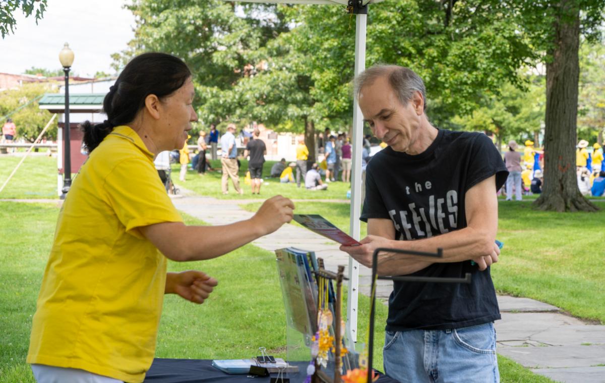 Bob Torsello at an information booth during a rally calling for an end to the persecution of the spiritual group in China in Goshen, N.Y., on July 22, 2023. (Cara Ding/The Epoch Times)