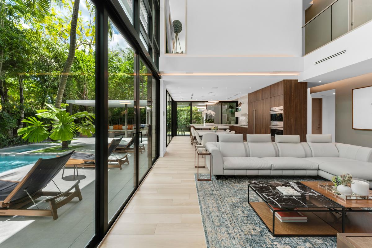 The airy and inviting living room looks out over the pool and lush tropical landscaping. (Courtesy of 1 Oak Studios/ONE Sotheby’s International Realty)