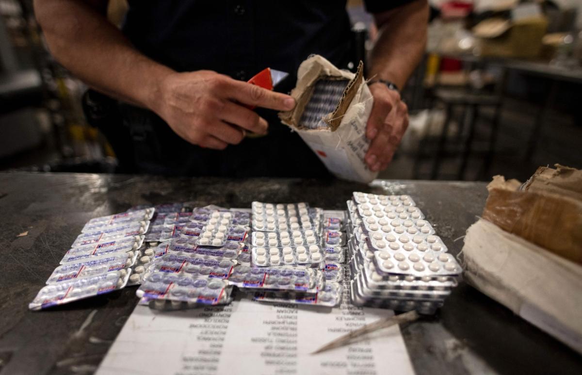 An officer from the U.S. Customs and Border Protection Trade and Cargo Division finds Oxycodone pills in a parcel at John F. Kennedy Airport's U.S. Postal Service facility in New York on June 24, 2019. (Johannes Eisele/AFP via Getty Images)