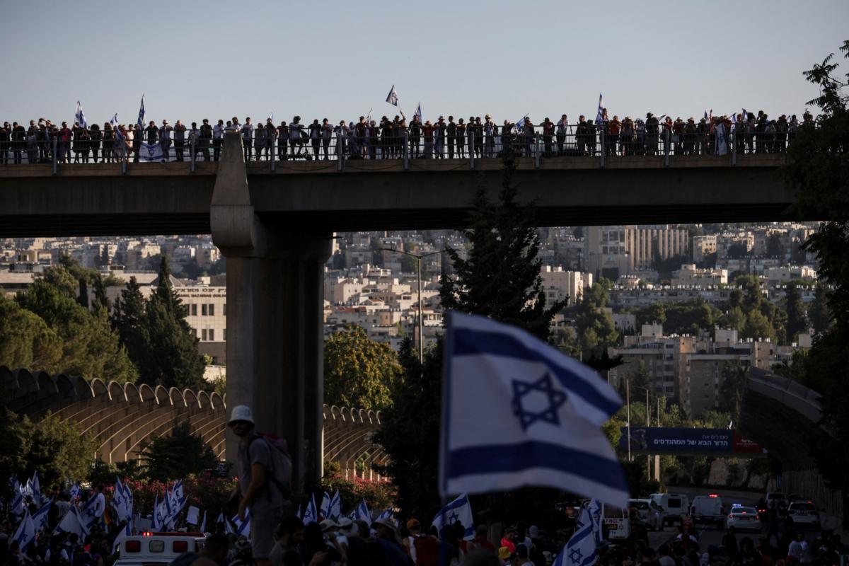 Protesters stand on a bridge at a demonstration following the parliament's vote on a contested bill that limits the Supreme Court's powers to void some government decisions, in Jerusalem, on July 24, 2023. (Ronen Zvulun/Reuters)