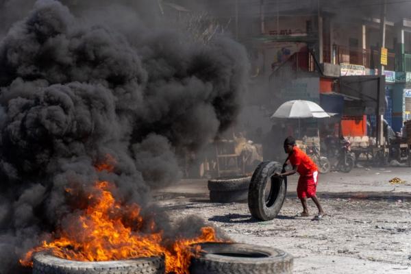 A protester adds a tire to a burning barricade during a police demonstration to protest the recent killings of six police officers by armed gangs, in Port-au-Prince, Haiti, on Jan. 26, 2023. (Richard Pierrin/AFP via Getty Images)