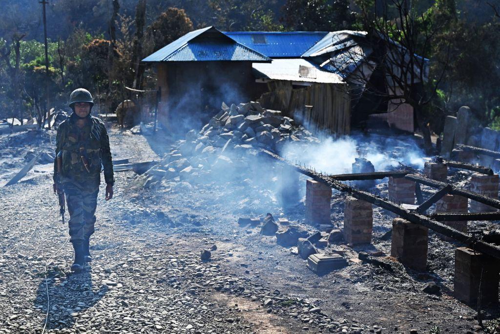 An Indian army soldier walks past the remains of a house that was set on fire by a mob in an area hit by ethnic violence, in Senapati district, in India's Manipur state, on May 8, 2023.  (Arun Sankar/AFP via Getty Images)