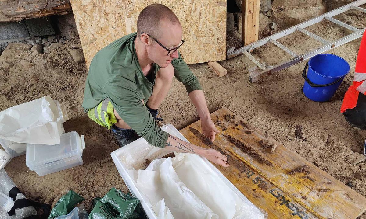 Archeologist Jo-Simon Frøshaug Stokke, from the Museum of Cultural History, inspects the remains of a Viking sword that they dated from between the 9th and 10th centuries. (Courtesy of Joakim Wintervoll, Agder county municipality)