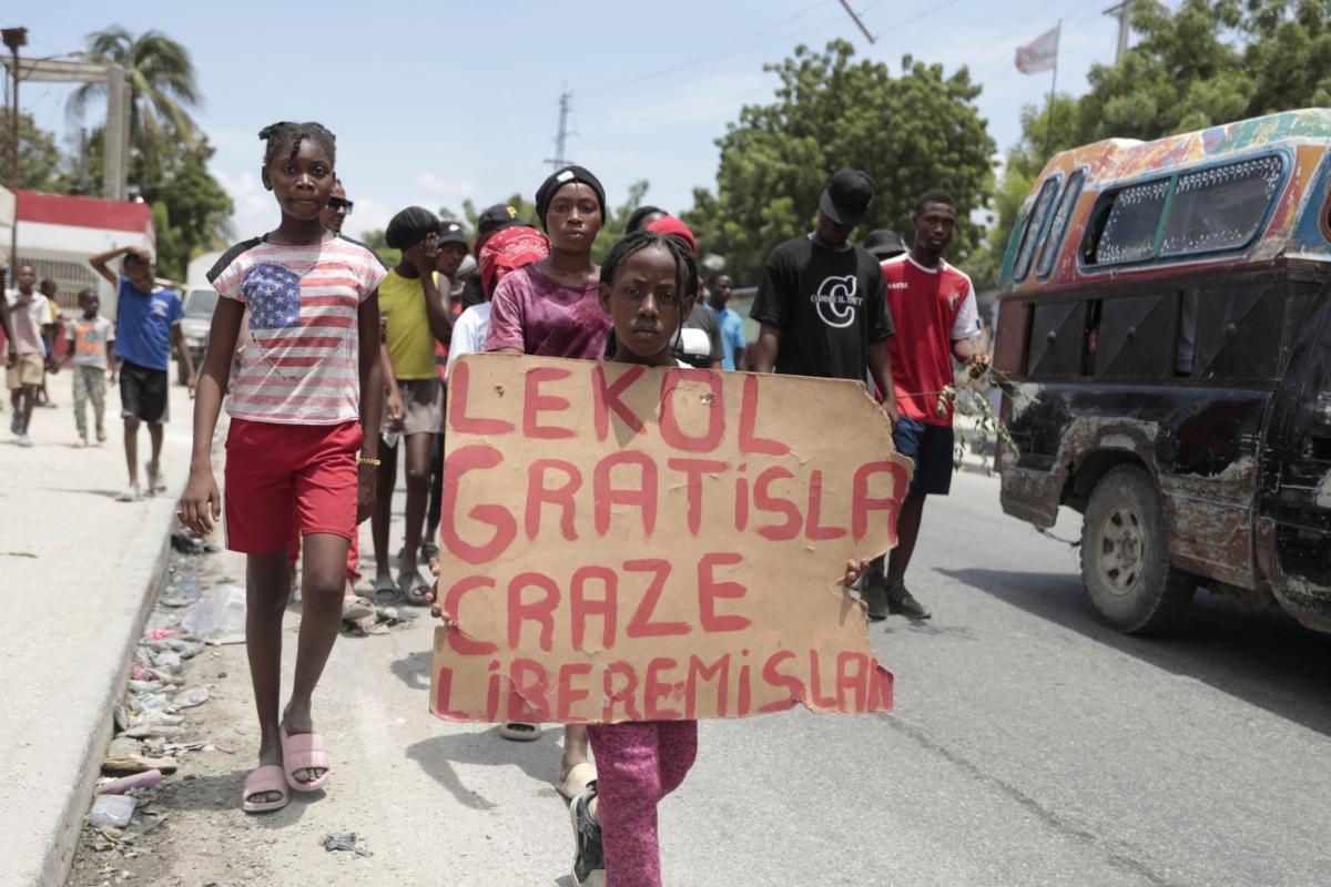 A girl carries a sign during a march to demand the freedom of New Hampshire nurse Alix Dorsainvil and her daughter, who were reported to be kidnapped, in the Cite Soleil neighborhood of Port-au-Prince, Haiti, on July 31, 2023. (Odelyn Joseph/AP Photo)