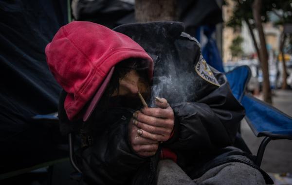 Spencer from the state of Washington lights up marijuana laced with other drugs in front of his tent on the street in the Tenderloin District in San Francisco on Feb. 23, 2023. (John Fredricks/The Epoch Times)