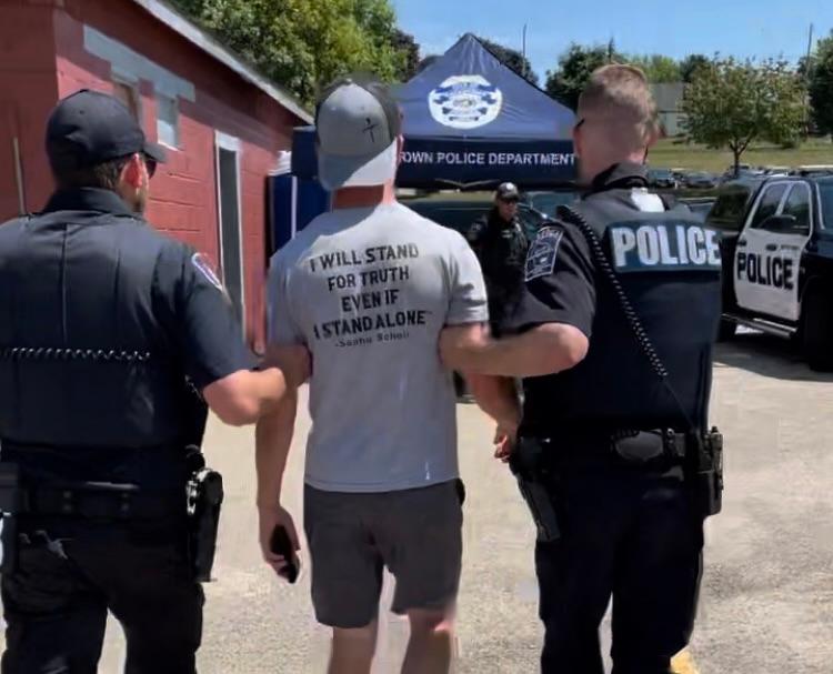 Police arrest Marcus Schroeder after he used a microphone to read The Bible in protest against a "child-friendly" drag event in Watertown, Wis., on July 29, 2023. (Courtesy of Marcus Schroeder)