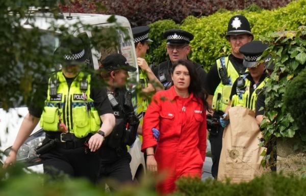 Greenpeace activists are led away by police after they climbed on the roof of Prime Minister Rishi Sunak's house in Richmond, North Yorkshire, and covered it in black fabric in protest at his backing for expansion of North Sea oil and gas drilling on Aug. 3, 2023. (PA Media)