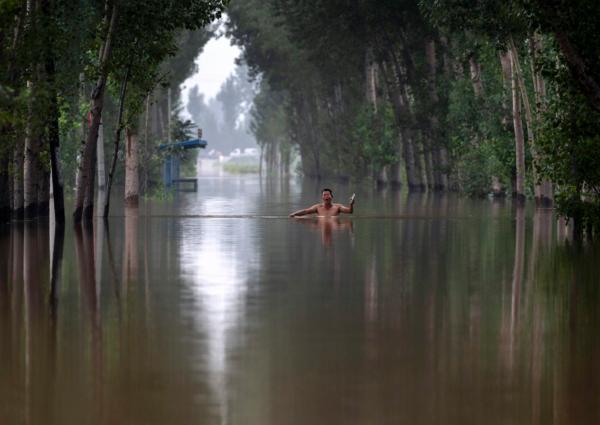 A local resident gestures as he walks in chest deep floodwaters in an area near Zhuozhou, Hebei Province, south of Beijing on Aug. 3, 2023. (Kevin Frayer/Getty Images)