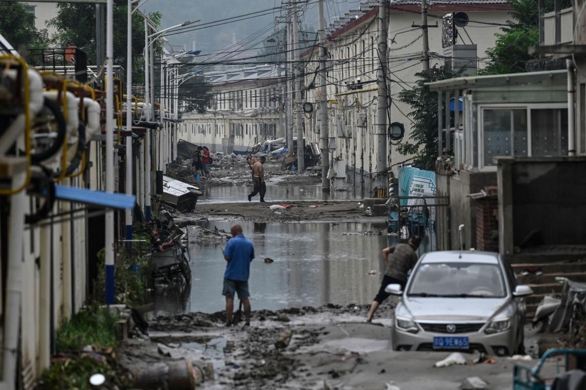 Residents clean up the street after flooding at a village following heavy rains in Beijing on August 3, 2023. (Jade Gao/AFP via Getty Images)