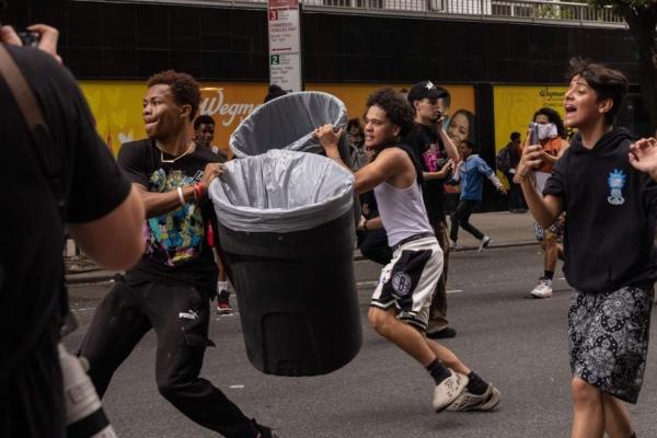 People throw trash bins at police officers during riots after Twitch streamer Kai Cenat announced a "giveaway" event, in New York's Union Square on Aug. 4, 2023. (Yuki Iwamura/AFP via Getty Images)