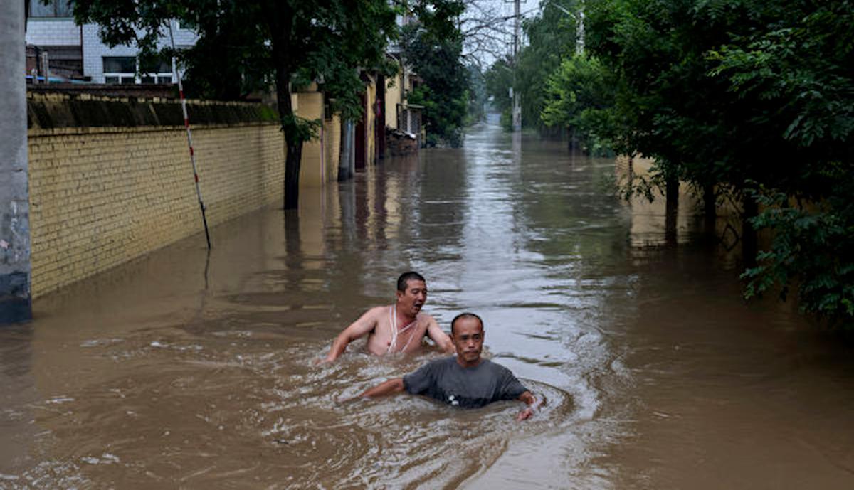 Local residents struggle in deep, fast-moving water as they make their way toward rescuers in a boat in an area inundated with floodwaters near Zhuozhou, Hebei Province, south of Beijing, on Aug. 3, 2023. (Kevin Frayer/Getty Images)