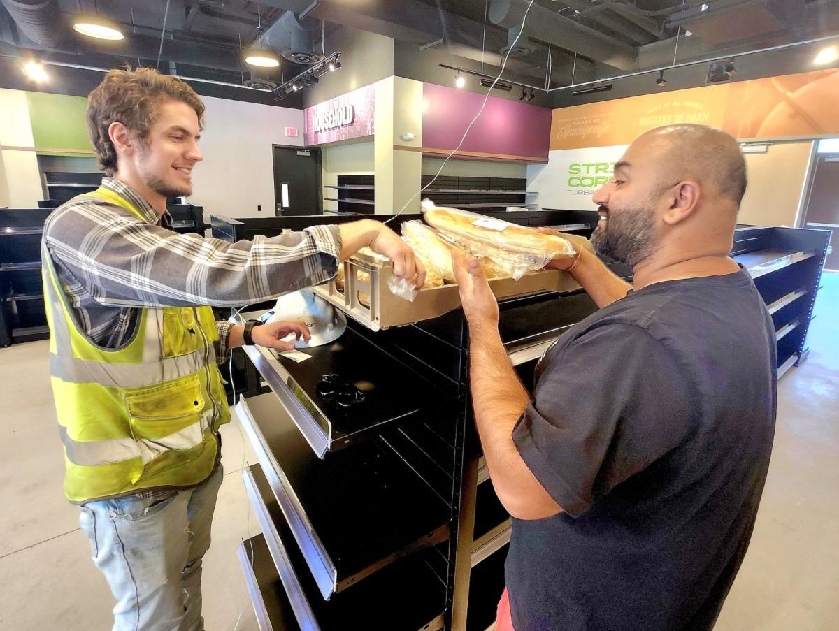 Culdesac Tempe construction manager Anders Engnell (L) and Vic Dhillon, owner of an on-site grocery store, prepared a shipment of fresh bread on Aug. 2, 2023. (Allan Stein/The Epoch Times)
