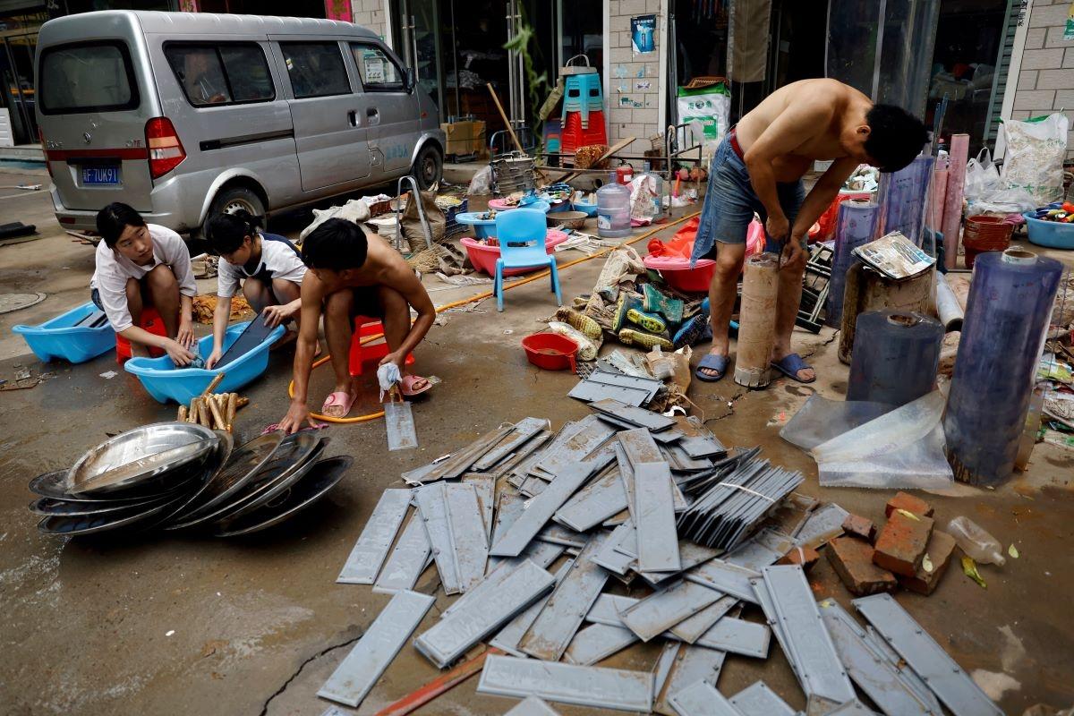 People clean muddied items outside a store after the rains and floods brought by remnants of Typhoon Doksuri in Zhuozhou, Hebei Province, China, on Aug. 7, 2023. (Tingshu Wang/Reuters)