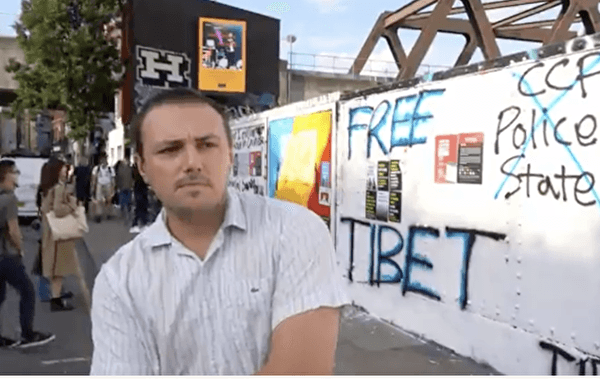 Jack, a Londoner who works in travel industry, stands next to the street art wall in East London. Aug. 7, 2023. (Wen Qing/The Epoch Times)