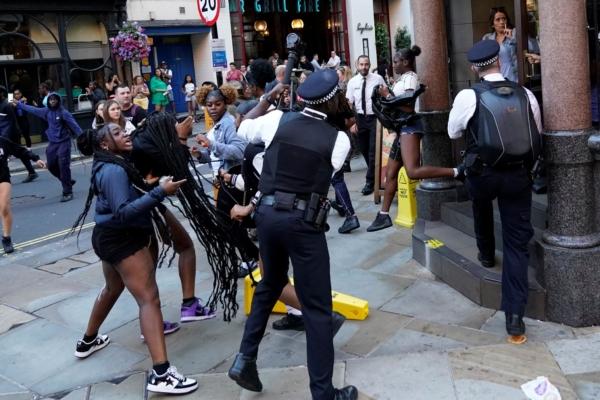 Police officers try to stop youths as they run out of a McDonald's store on Oxford Street in central London on Aug. 9, 2023 (PA)