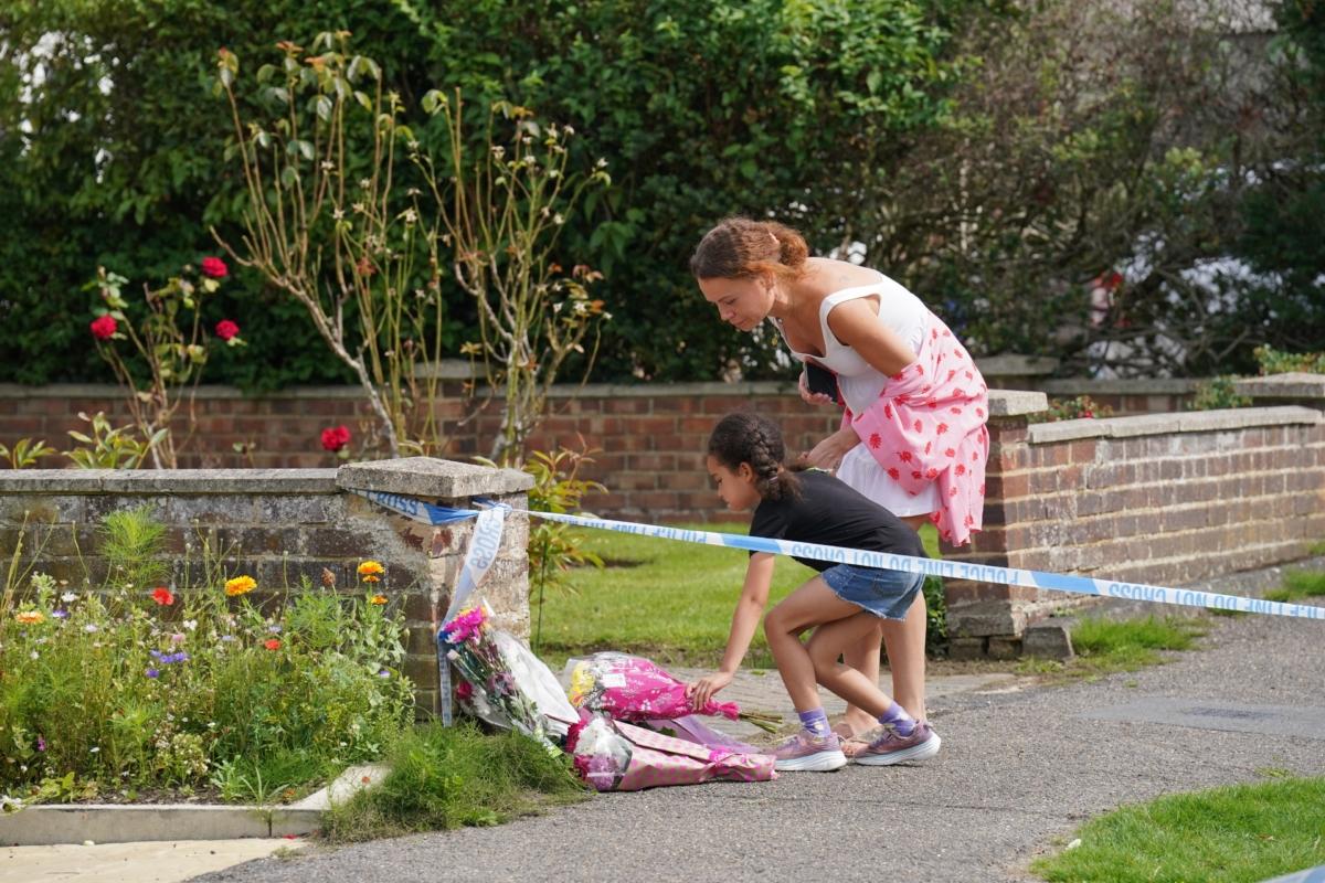 People lay flowers outside a property on Hammond Road in Woking, Surrey, on Aug. 11, 2023, one day after a 10-year-old girl was found dead on the property. (Jonathan Brady/PA)