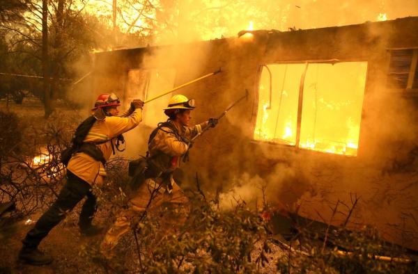 Firefighters try to keep flames from a burning home from spreading to a neighboring apartment complex as they battle the Camp Fire in Paradise, Calif., on Nov. 9, 2018. (Justin Sullivan/Getty Images)