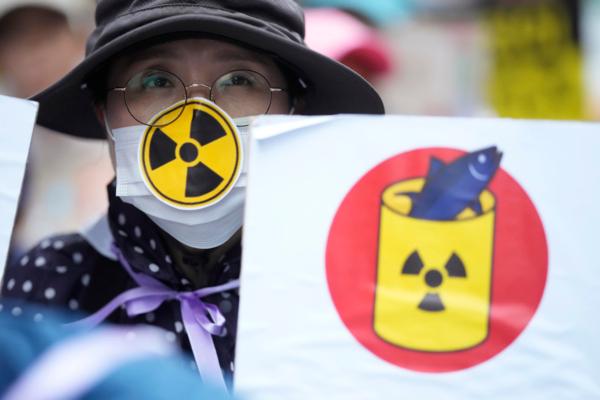 A person holds a poster to protest Japan's plan to release treated radioactive water from the wrecked Fukushima nuclear power plant, during a match along a street in Seoul, South Korea, on Aug. 12, 2023. (AP Photo/Lee Jin-man)